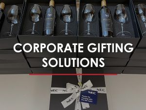 A photo of a stack of wine bottles and wine glasses in black boxes with the text "CORPORATE GIFTING SOLUTIONS” and the thank you card reads “Thanks for meeting with the NEC team NEC.”